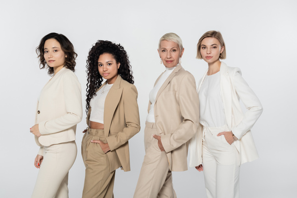 Empresarias multiétnicas en ropa formal posando aisladas en concepto de feminismo gris - Foto, Imagen