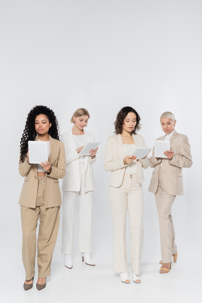Empresarias interraciales usando tabletas digitales sobre fondo gris  - Foto, Imagen