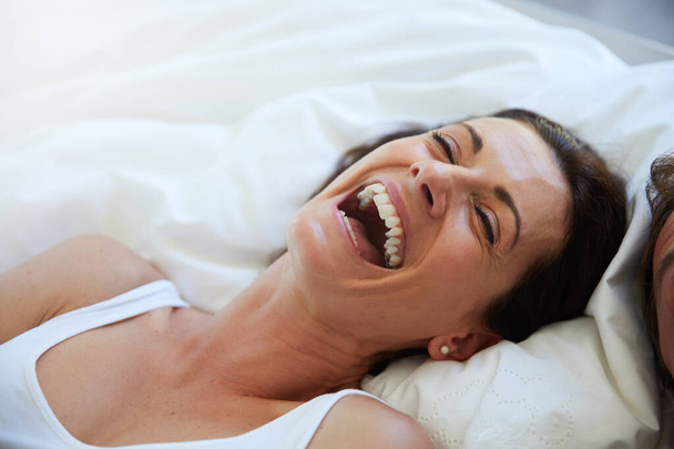 Mikään ei ole parempaa kuin nauru tunnelman kohentamiseksi. Laukaus nainen nauraa, kun rentoudut sängyssä miehensä rinnalla. - Valokuva, kuva