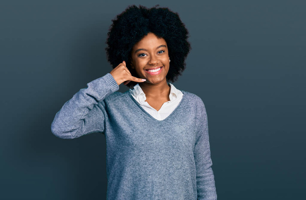Молодая африканская американка в деловой одежде улыбается, делая телефонный жест рукой и пальцами, как будто разговаривает по телефону. коммуникационные концепции.  - Фото, изображение