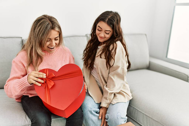Young woman surprising her girlfriend with valentine gift at home. - Photo, Image