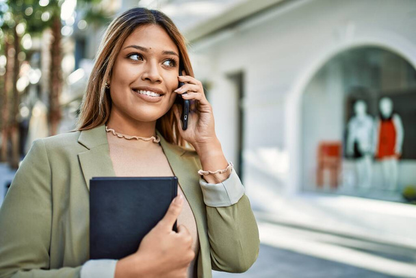 fiatal latin nő mosolygós magabiztos beszél az okostelefon az utcán - Fotó, kép