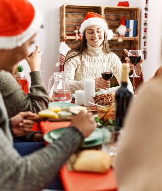 Gruppe junger Leute lächelt glücklich und prostet Weihnachten zu Hause mit Wein zu. - Foto, Bild