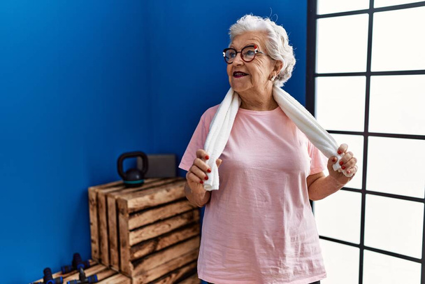 Idősebb ősz hajú nő, aki sportruházatot visel, magabiztosan mosolyog a sportközpontban. - Fotó, kép