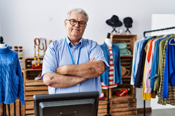 Senior man with grey hair working as manager at retail boutique happy face smiling with crossed arms looking at the camera. positive person.  - 写真・画像