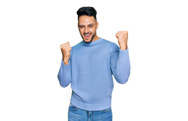 Young arab man wearing casual clothes screaming proud, celebrating victory and success very excited with raised arms  - Fotó, kép