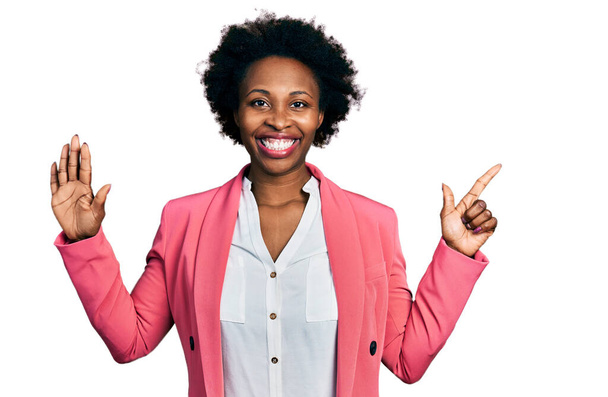 Африканська американка з волоссям афро в діловій куртці показує і вказує вгору з пальцем номер сім, посміхаючись впевнено і щасливо.  - Фото, зображення