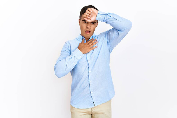 Mladý hispánec v obchodní košili stojící nad izolovaným pozadím a dotýkající se čela kvůli nemoci a horečce, chřipce a nachlazení, virové nemoci  - Fotografie, Obrázek