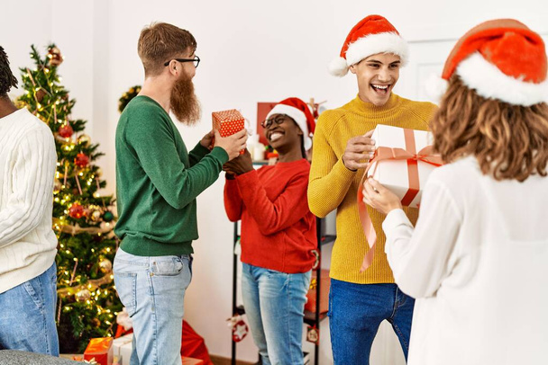 Ομάδα νέων που δίνουν χριστουγεννιάτικα δώρα στο σπίτι. - Φωτογραφία, εικόνα