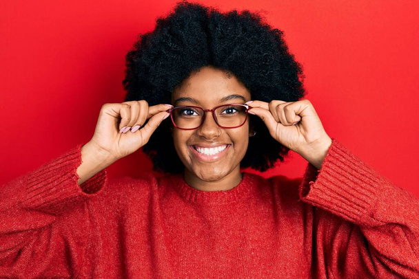 Jonge Afro-Amerikaanse vrouw met een bril die glimlacht met een vrolijke en coole glimlach op haar gezicht. tanden tonen.  - Foto, afbeelding