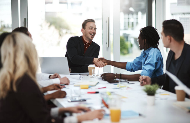 Welcoming new members to their dynamic team. Shot of businesspeople shaking hands during a meeting in an office. - Foto, Bild
