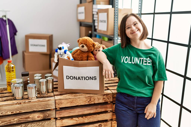 Bruna donna con sindrome di Down in piedi da scatola con giocattoli donati in stand donazioni - Foto, immagini