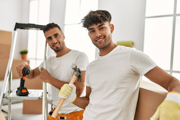 Dois homens hispânicos casal sorrindo casa reparadora confiante em nova casa - Foto, Imagem
