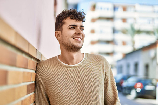 Junger hispanischer Mann lächelt glücklich in der Stadt - Foto, Bild