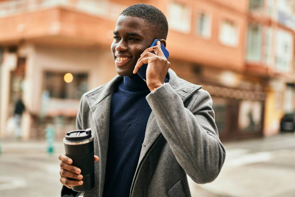 Jeune homme afro-américain parlant sur le smartphone boire du café à la ville - Photo, image