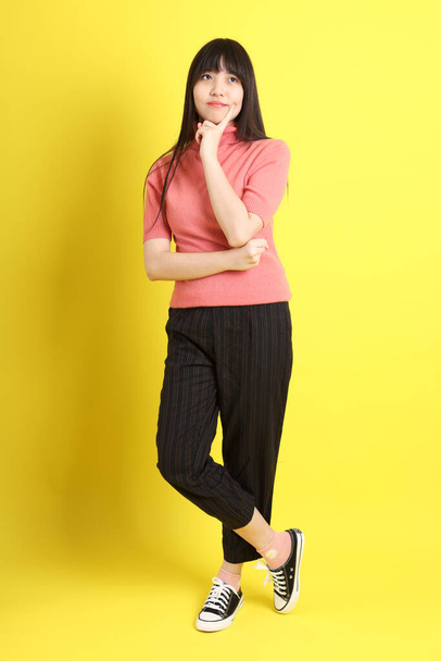 The teen Asian girl with casual dressed standing on the yellow background. - Photo, Image
