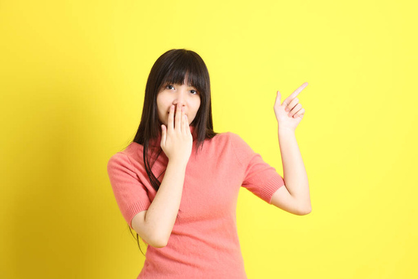 The teen Asian girl with casual dressed standing on the yellow background. - Фото, изображение