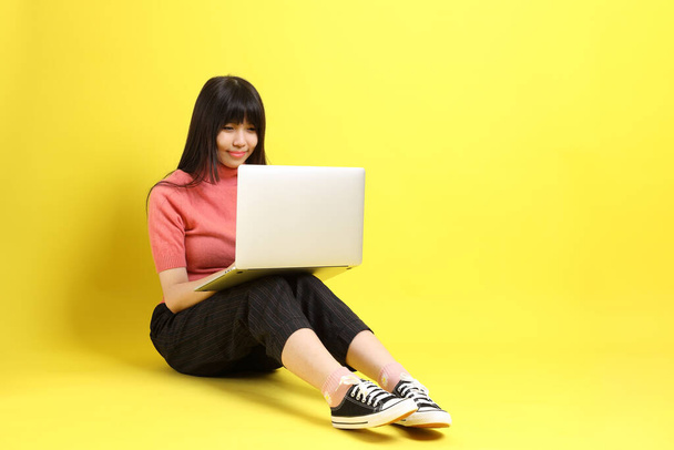 L'adolescent asiatique fille avec casual habillé assis sur le fond jaune. - Photo, image