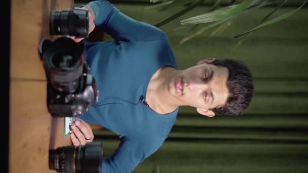 Video-Lektion über die Wahl des fotografischen Equipments und wie man damit arbeitet. Muslime filmen sich selbst mit einer Kamera, die ein Schild hält. vertikales Video. Online-Tutor, Mentor. - Filmmaterial, Video