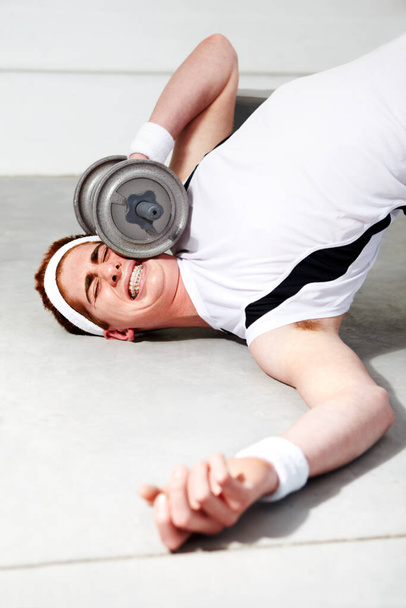 Het gewicht van de verwachting is te groot. Een jongeman probeert zware gewichten op te heffen in de sportschool en wordt verpletterd door een halter.. - Foto, afbeelding