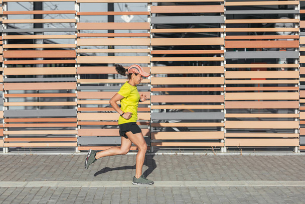 Латиноамериканка бегает на свежем воздухе, здоровый образ жизни. Желтый цвет - Фото, изображение
