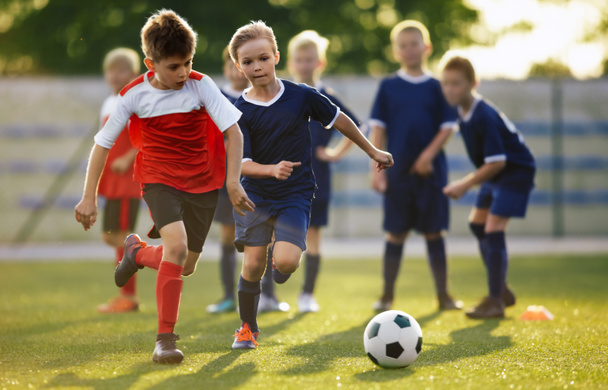 Fiatal fiúk foci edzős játékot játszanak. Junior labdarúgó edzés verseny játékosok között futó párbaj és rugdossa a focilabda. Képzés és labdarúgó-mérkőzés ifjúsági focicsapatok között - Fotó, kép
