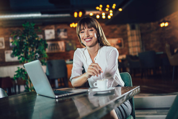 Привлекательная женщина в кафе с ноутбуком во время кофе-брейка
 - Фото, изображение