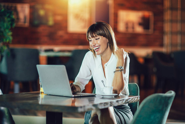 Mooie aantrekkelijke vrouw in het café met een laptop met een koffiepauze - Foto, afbeelding