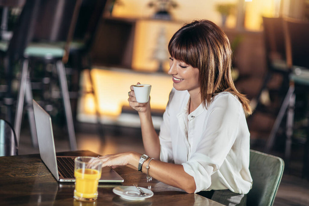 Beautiful attractive woman at the cafe with a laptop having a coffee break - 写真・画像