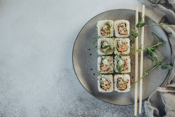 Sur un fond gris dans une assiette grise sushi épicé au saumon frit - Photo, image