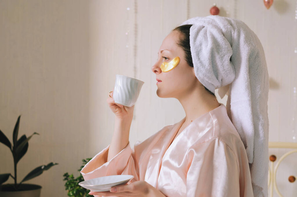 Young happy woman doing facial skin care procedures. Lies in bed in pajamas in a cozy home. Beauty routine. Skin care cosmetic concept - Valokuva, kuva