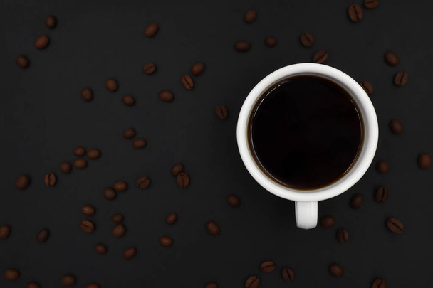 вид зверху на чорну гарячу каву з білою керамічною чашкою. Смажені кавові зерна лежать на темному фоні. з копіюванням простору для додавання тексту
 - Фото, зображення