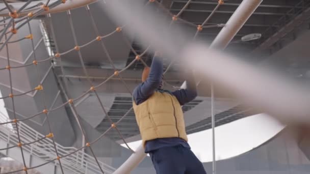 Медленно убежденный афроамериканец в теплой одежде подтягивается под мостом во время тренировок на открытом воздухе холодным утром - Кадры, видео