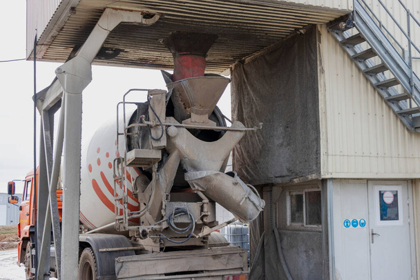 Betoniarka ładuje beton w fabryce. Transport betonu na plac budowy. Sprzęt budowlany do dostawy betonu - Zdjęcie, obraz