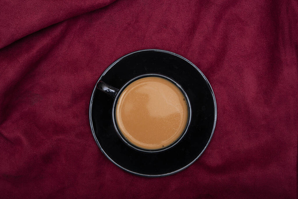 Top view of hot black tea cup on red bedsheet. - Foto, Imagen