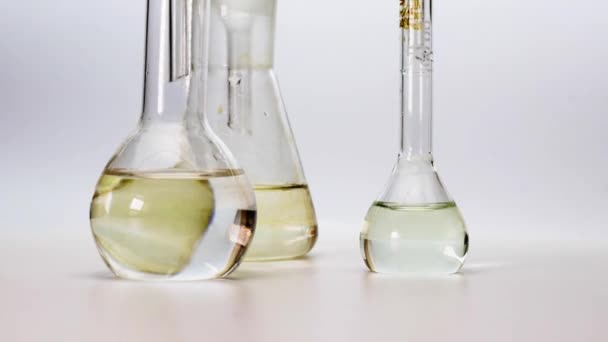 Laboratory flasks with liquid close-up on a white background. Medical laboratory researches and analyses. Reagents of different colors. - Footage, Video