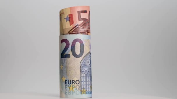 A feltekert eurobankjegyek fehér alapon forognak. Közelkép. Üzlet és pénzügy. A készpénz fogalma és a pénzügyi eszközök felhalmozódása. - Felvétel, videó