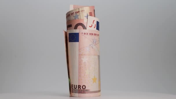 A feltekert eurobankjegyek fehér alapon forognak. Közelkép. Üzlet és pénzügy. A készpénz fogalma és a pénzügyi eszközök felhalmozódása. - Felvétel, videó