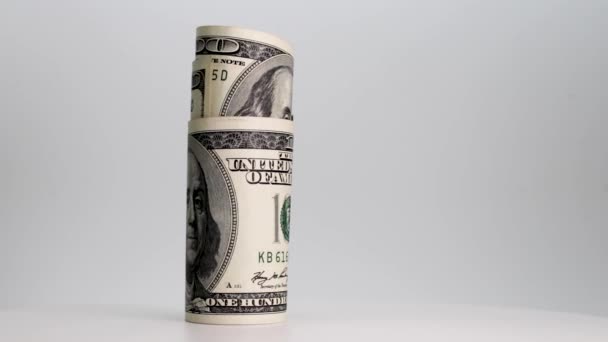 Dollar biljetten opgerold in een buis draaien op een witte achtergrond. Een close-up. Bedrijven en financiën. Het begrip liquide middelen en de accumulatie van financiële activa. - Video