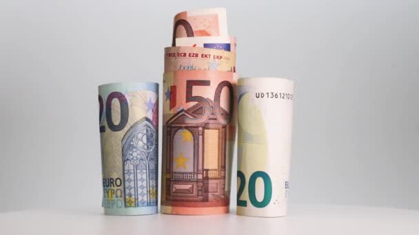 Opgerolde eurobankbiljetten draaien op een witte achtergrond. Een close-up. Bedrijven en financiën. Het begrip liquide middelen en de accumulatie van financiële activa. - Video