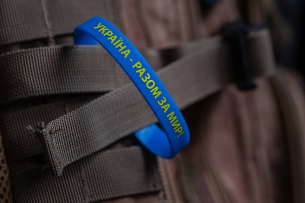 Жовто-синій браслет з написом українською: "Україна - разом заради миру!" Запобігання воєнних дій в Україні. Концепція миру - Фото, зображення