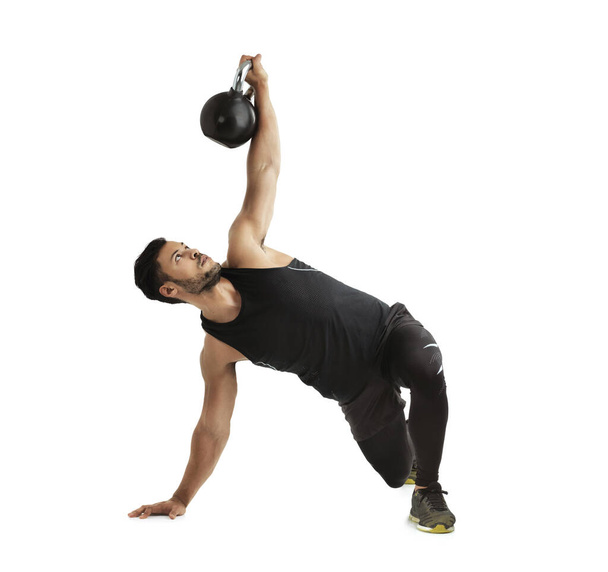 Studio shot of a fit young man working out with a kettle bell against a white background. - Foto, immagini