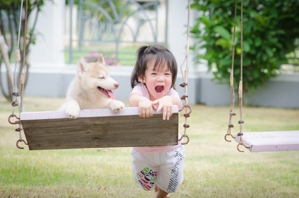 Asya bebek bebek salıncak ile köpek yavrusu üzerinde - Fotoğraf, Görsel
