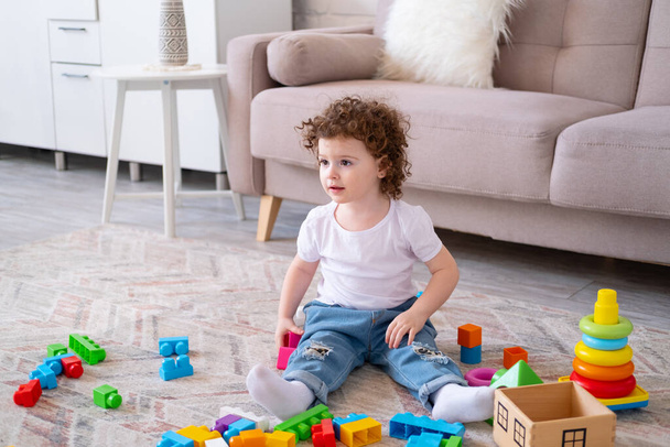 curly child girl playing with pyramid and constructor at home. early children development - 写真・画像