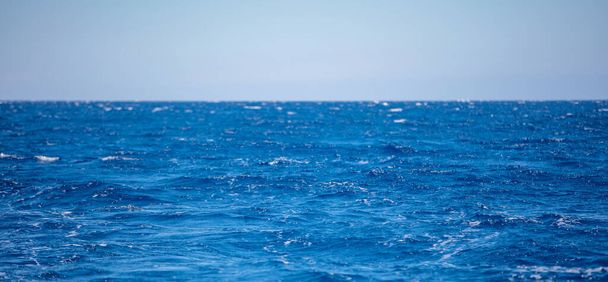 Aaltoileva meriveden pinta syvän sininen väri, pienet aallot vaahdolla, sininen taivas tausta. Egeanmeren alue - Valokuva, kuva