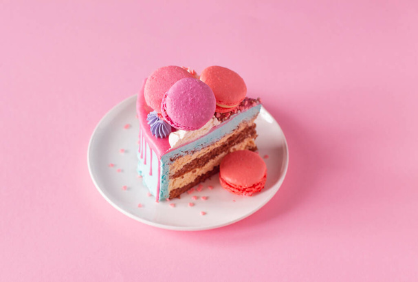 piece of cake with pink and blue decor on white plate on pink background - Foto, imagen