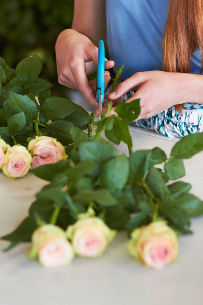 Shes learned the skills necessary for great arranging. High angle shot of a florists hands trimming leaves off of rose stems. - Φωτογραφία, εικόνα