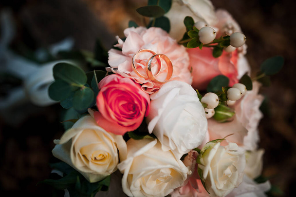 Золотые обручальные кольца, красивый свадебный букет цветов - Фото, изображение
