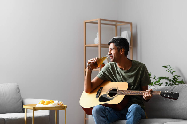 Hombre guapo con guitarra bebiendo cerveza en casa - Foto, Imagen
