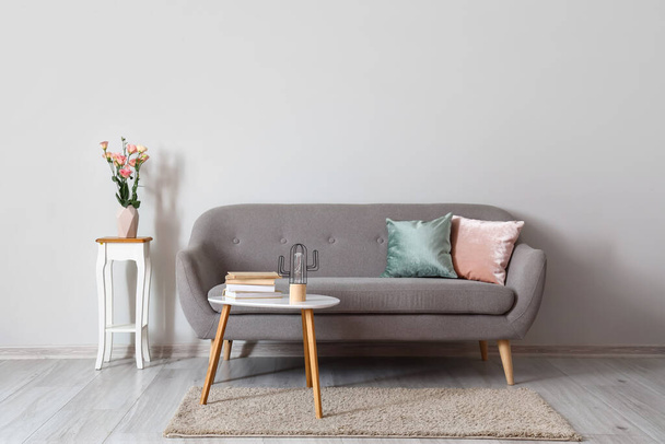 Acogedor sofá con mesas cerca de la pared de luz - Foto, Imagen